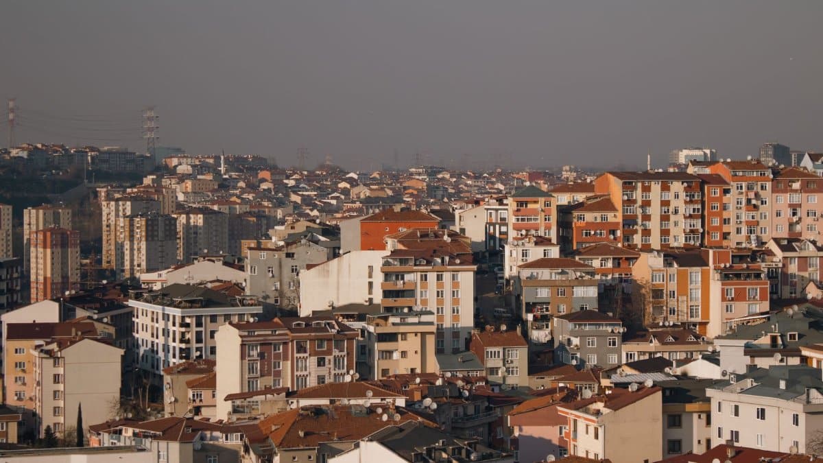 A city view showing densely packed residential buildings under a smoggy sky, highlighting urban environmental issues.