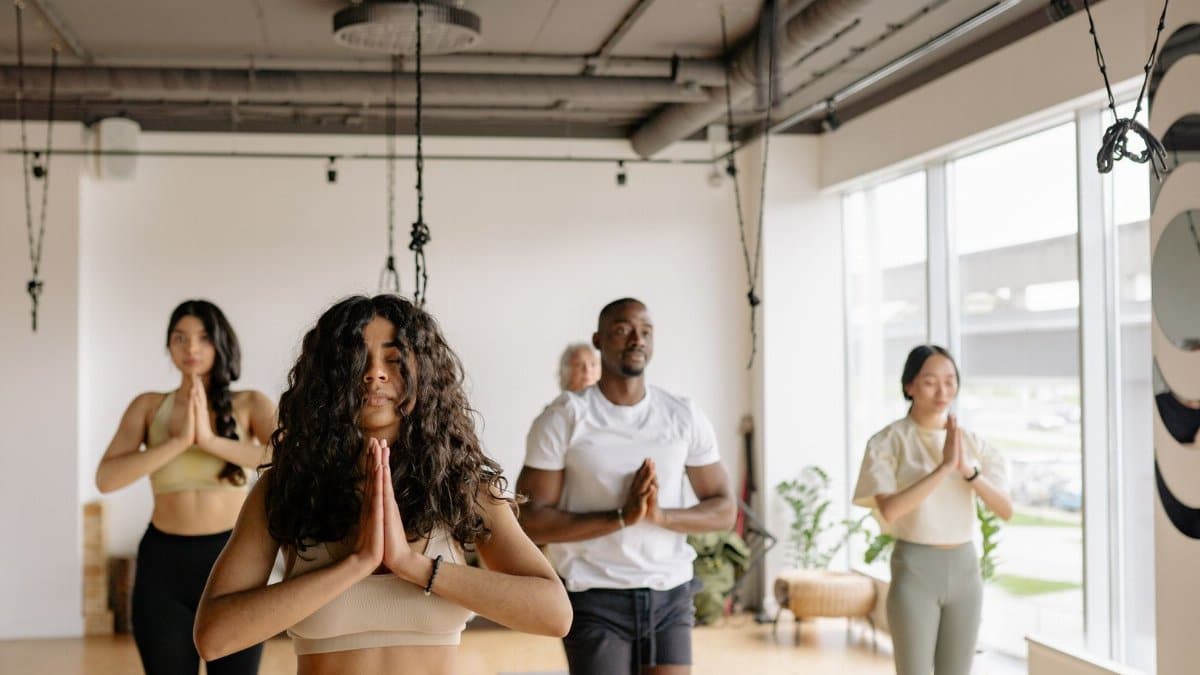 A multicultural group of adults practicing yoga poses together in a bright studio.