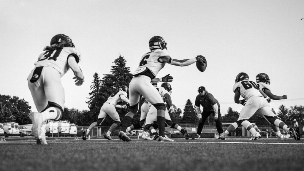 Energetic black and white image of football players practicing, highlighting teamwork and action.