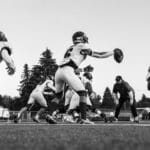 Energetic black and white image of football players practicing, highlighting teamwork and action.
