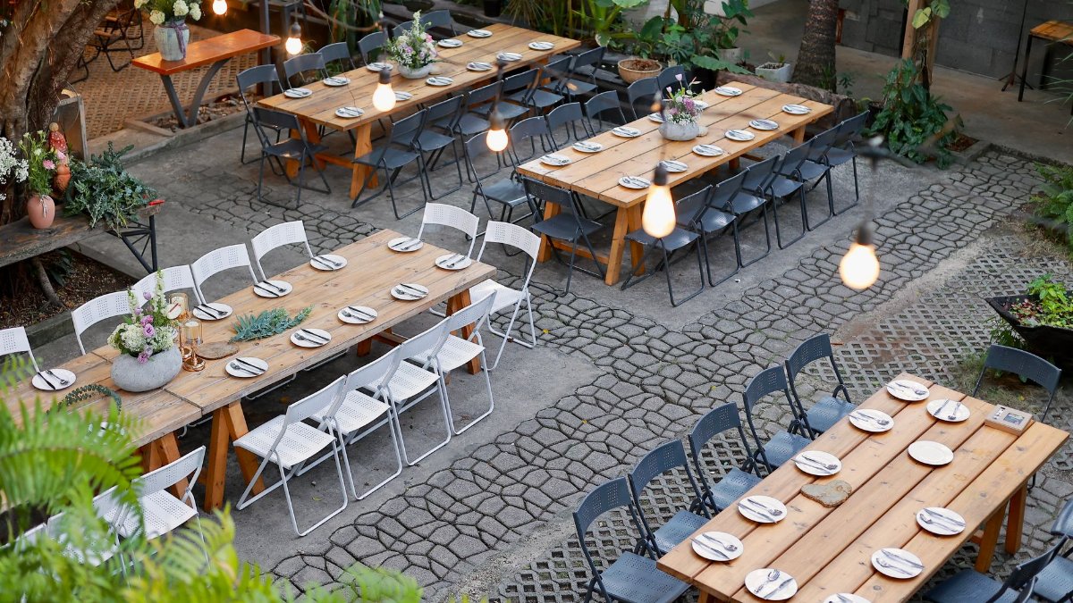 Scenic outdoor venue setup with rustic tables and floral decorations.