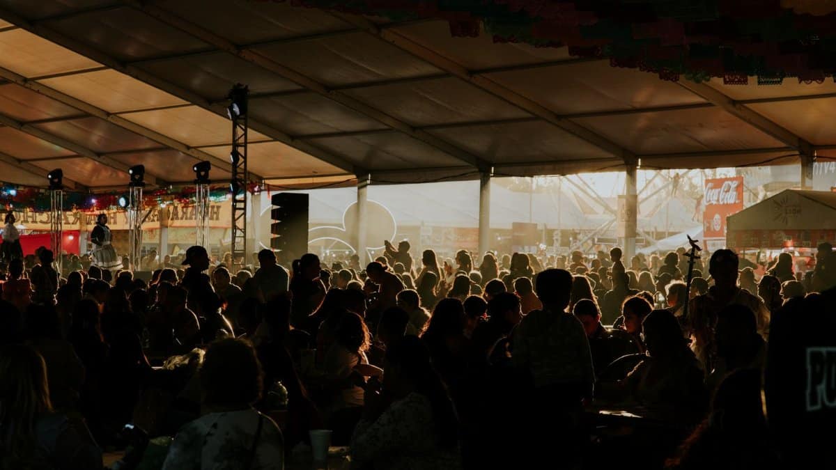 Silhouetted festival crowd enjoying an indoor event under a large tent, immersed in music and atmosphere.