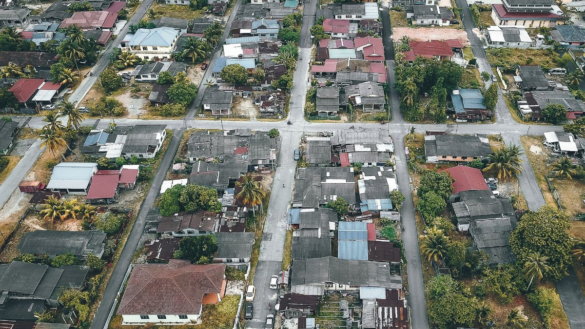 Aerial view of town with aged building facades near straight roadways and trees in daylight