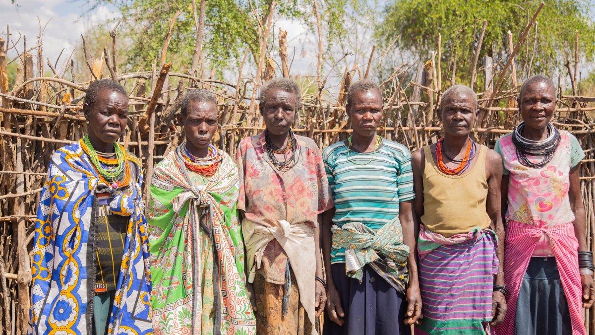 Group of tribal women in traditional attire standing outdoors.