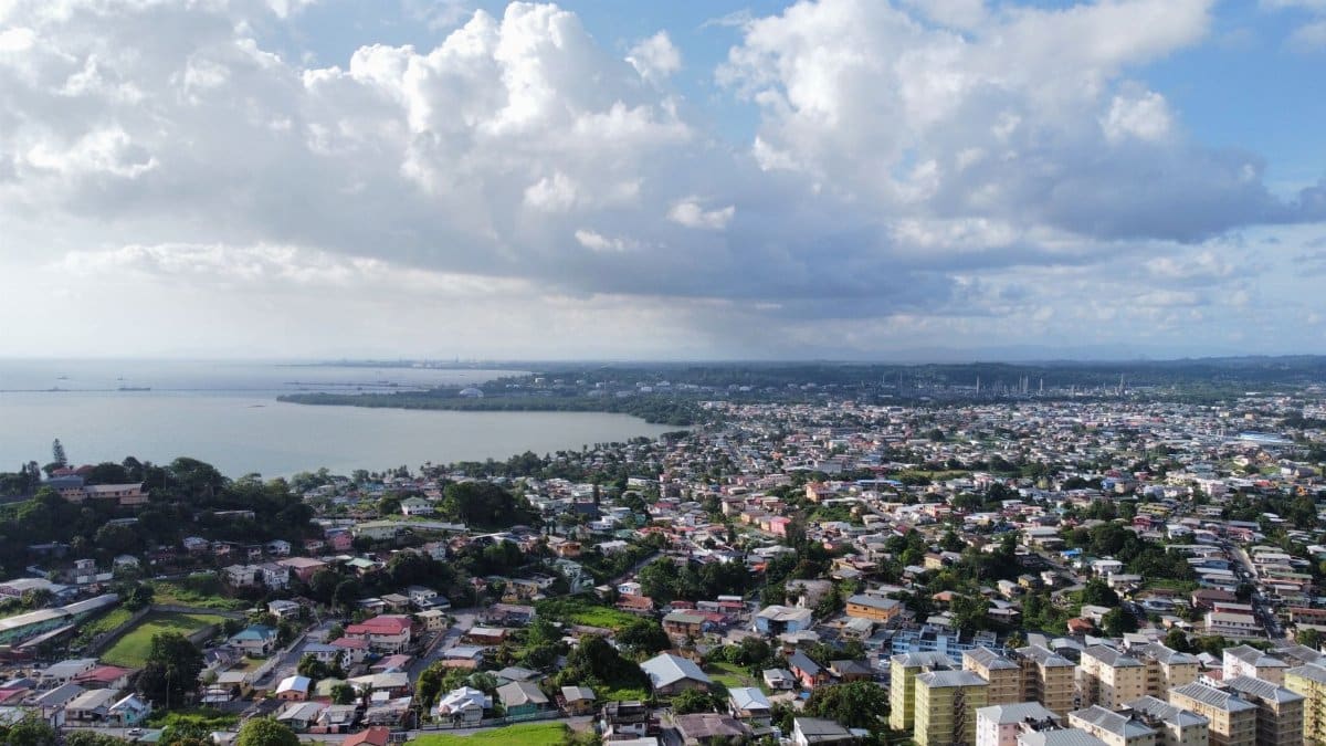 A stunning aerial view of a cityscape with lush greenery and blue waters under a vibrant sky.