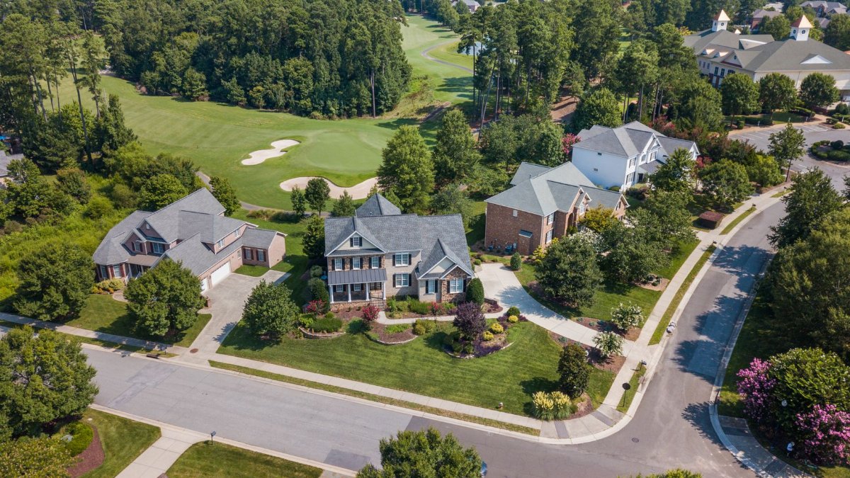 Aerial view of suburban neighborhood with lush greenery and golf course in Raleigh, NC.