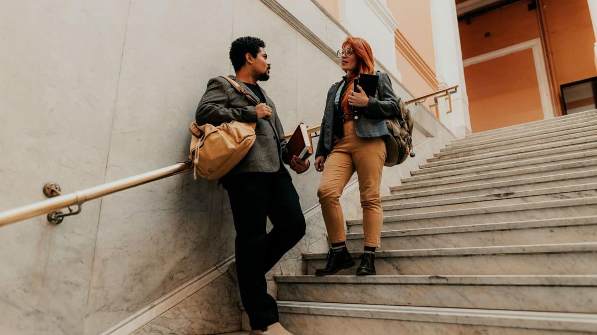 Two university students walking and conversing on an indoor staircase. Captured in Buenos Aires.