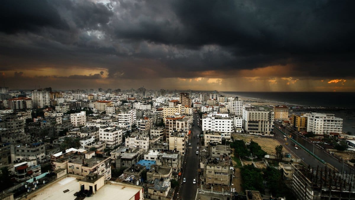Moody city view of Gaza under dark clouds with rain on the horizon.