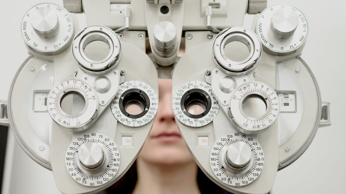 Woman diagnosing vision on refractor testing device during eye examination in modern ophthalmology clinic