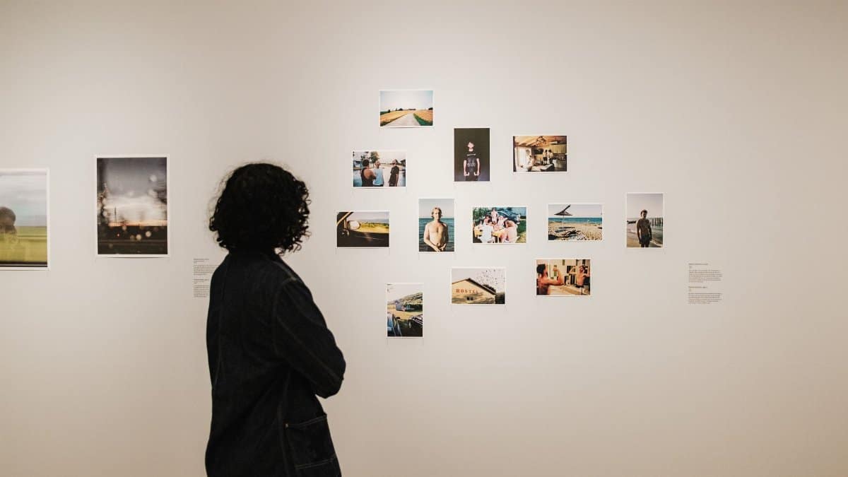 Individual viewing a photo collection on a gallery wall, showcasing various artworks.