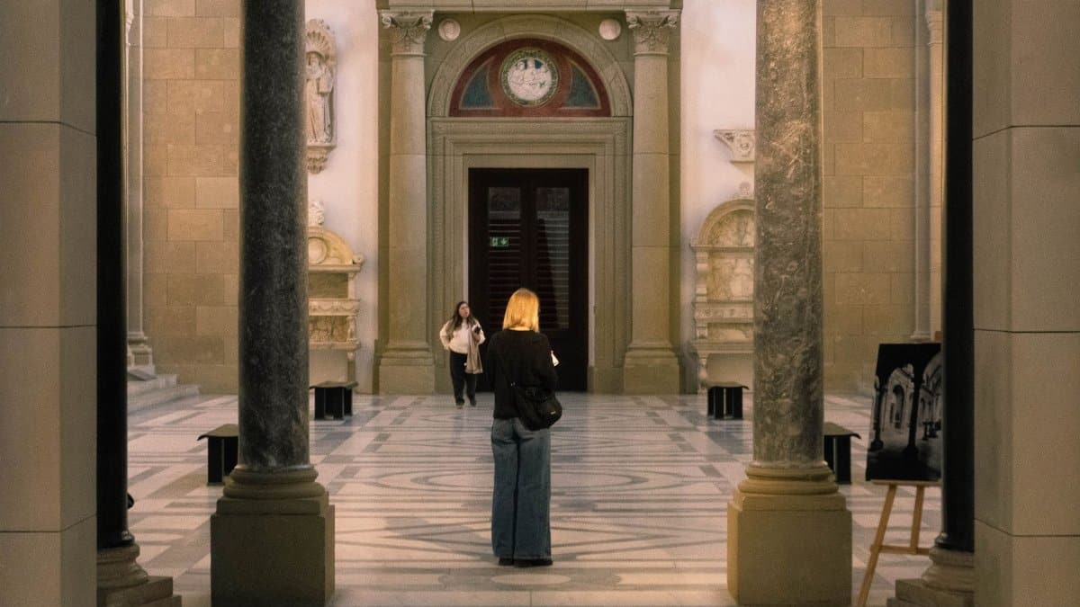 Two visitors explore the grand hall of a Berlin museum, showcasing its architectural beauty.