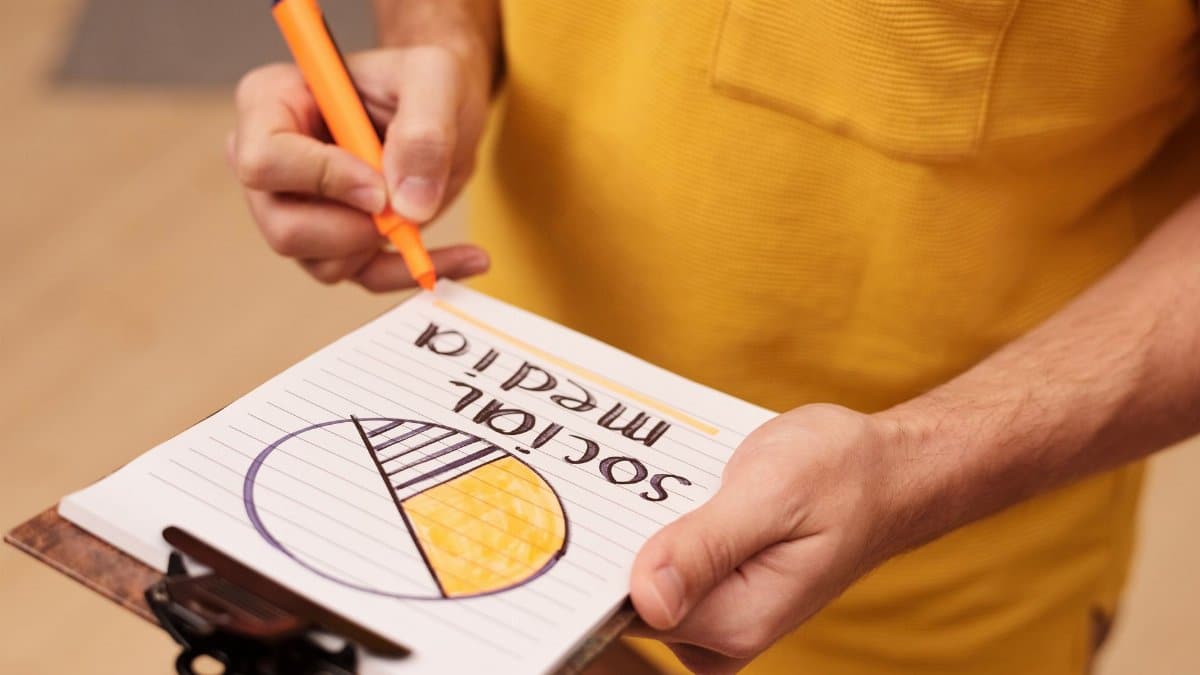 Person draws a social media pie chart on clipboard with orange marker.