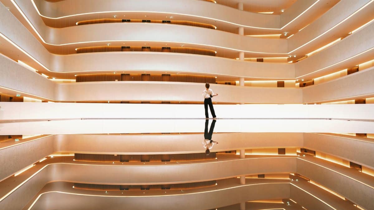 Modern elegant interior with a symmetrical design and reflective surfaces, featuring a person for scale.