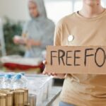 Volunteer holding a free food sign at a donation center, promoting charity and aid.
