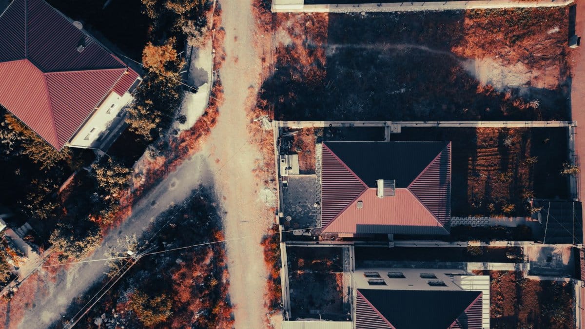 Aerial view showcasing suburban houses with red roofs and adjacent streets.