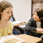 Two students in a classroom interacting with each other during a lesson.