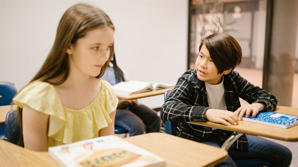 Two students in a classroom interacting with each other during a lesson.