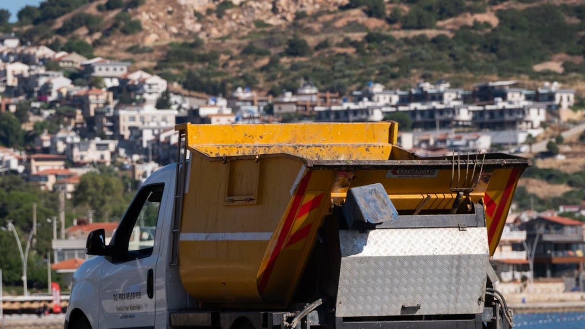 A waste collection truck parked by a scenic coastal road in Foça, İzmir, Türkiye.