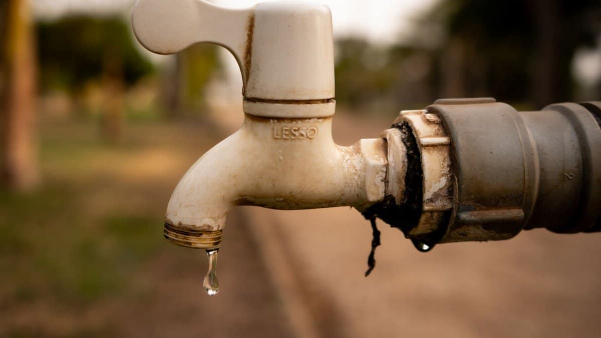 A close-up shot of a water droplet falling from an outdoor tap, highlighting water conservation issues.