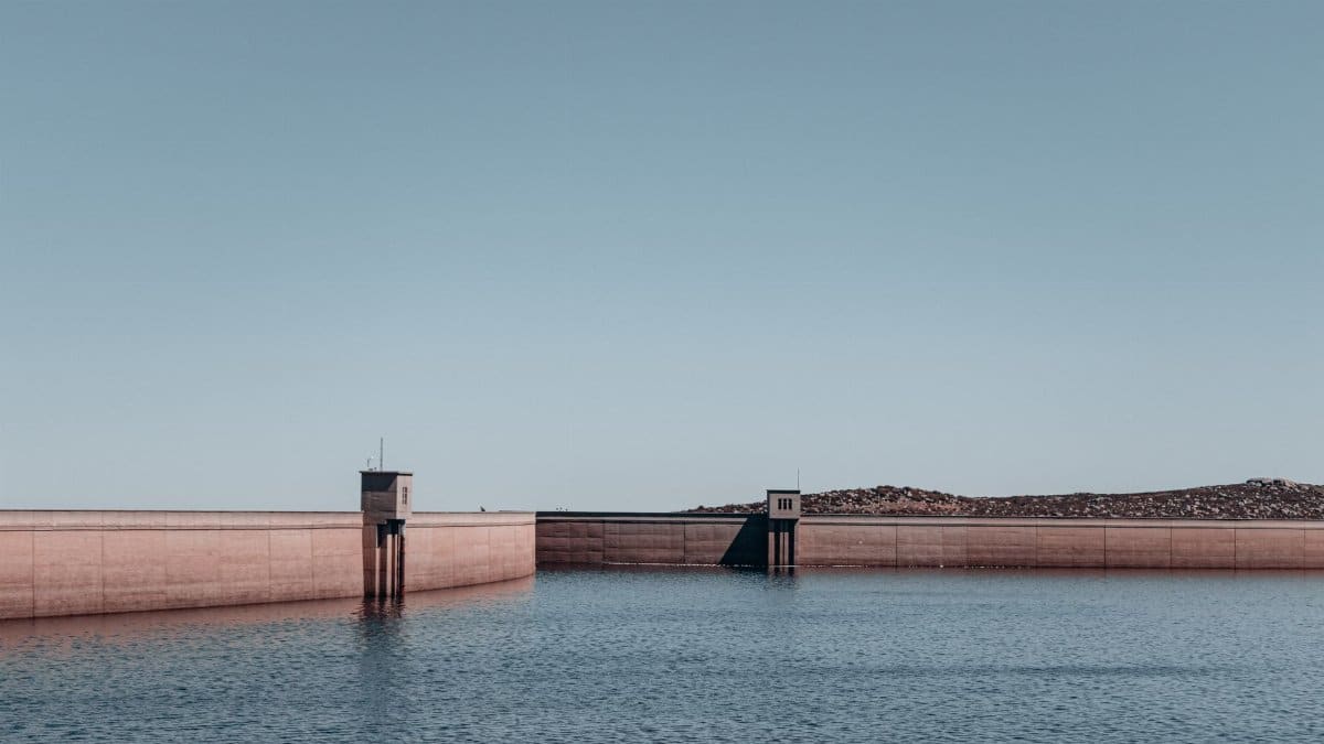 Drone shot of a large concrete water dam with clear skies in the background.