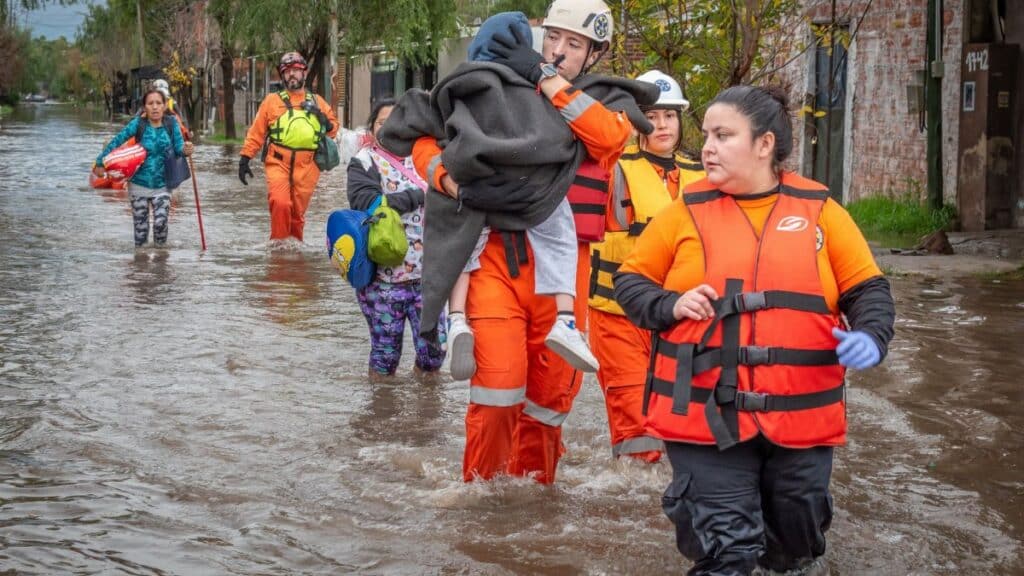 Rescue workers in orange gear helping people during a flood, showcasing bravery and teamwork.