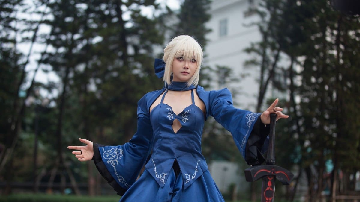 A person in a detailed blue cosplay costume holding a sword, outdoors.