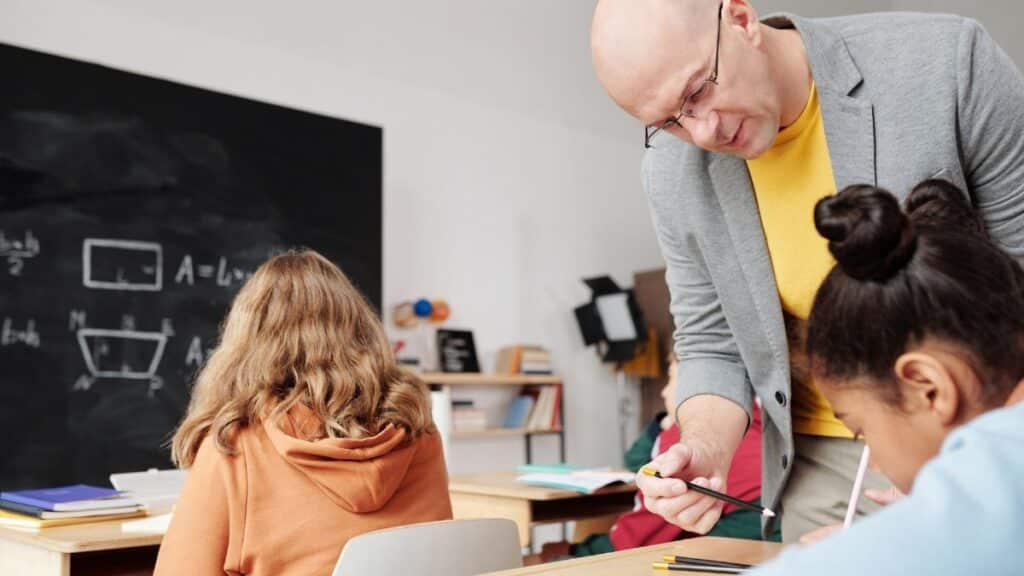 Teacher helping students in classroom, enhancing learning with personalized attention.