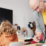 Teacher helping students in classroom, enhancing learning with personalized attention.