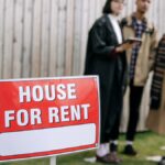 Three adults examining a house for rent sign outdoors, depicting diverse and inclusive interest in rental properties.