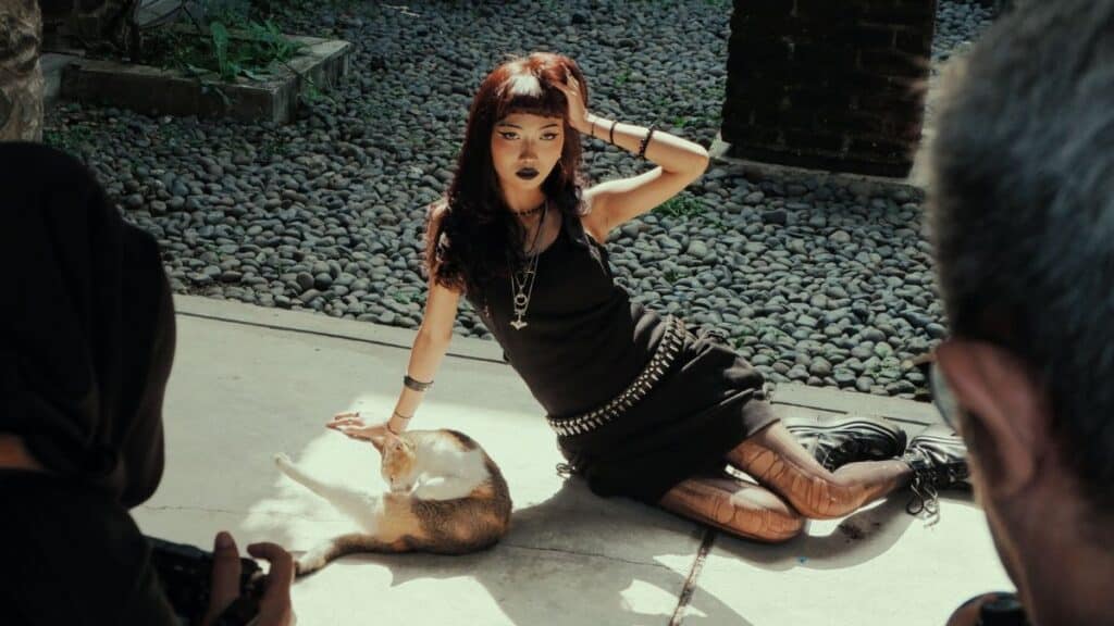 Artistic street photography capturing a model posing with a cat, framed by photographers.
