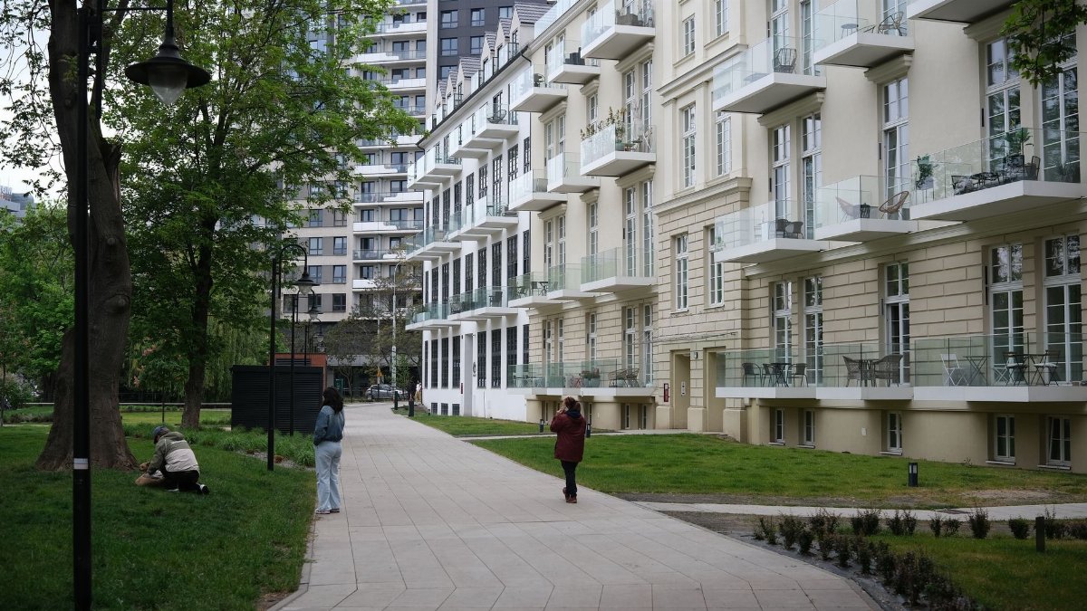 Contemporary apartment buildings next to a lush city park with people enjoying the outdoor space.