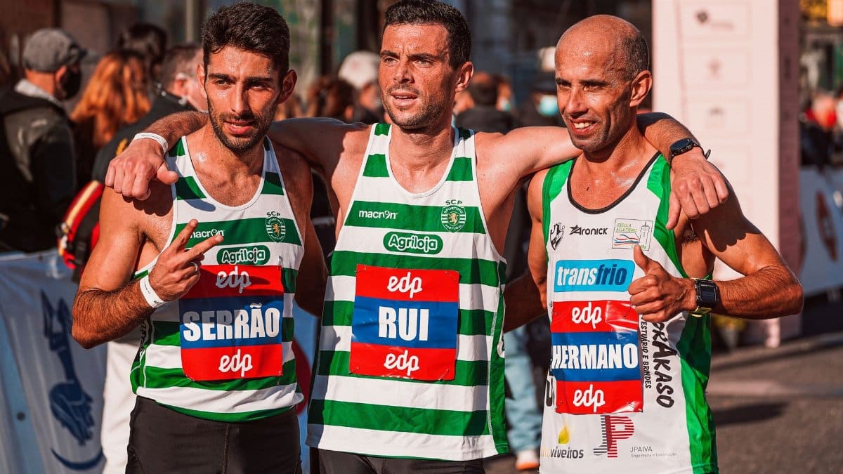 Three male marathon runners celebrating after finishing a race, displaying camaraderie and sportsmanship.