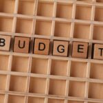 Wooden Scrabble tiles spelling 'budget' on a textured wooden grid, symbolizing financial planning.