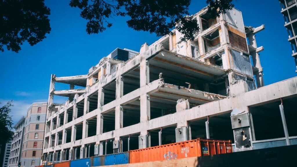 A partially demolished building under clear blue skies, showcasing urban decay and modern architecture.