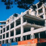 A partially demolished building under clear blue skies, showcasing urban decay and modern architecture.