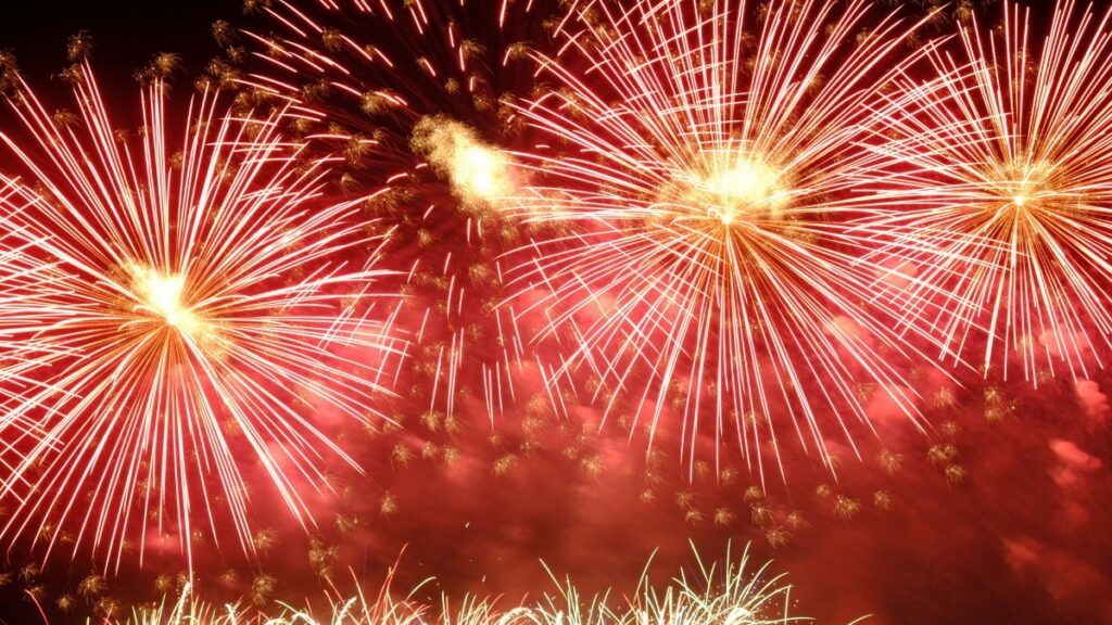 Vibrant red fireworks exploding in the night sky, creating a stunning visual spectacle.