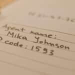 Handwritten document with agent name and ID code, showcasing personal handwritten text.