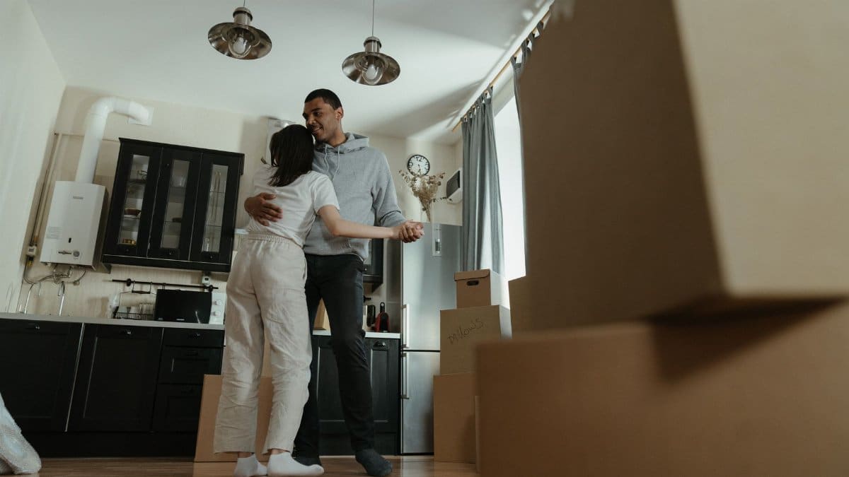 Happy couple dancing together in their new home filled with moving boxes, celebrating new beginnings.