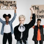 Diverse women protesting with placards and megaphone in a studio setting.
