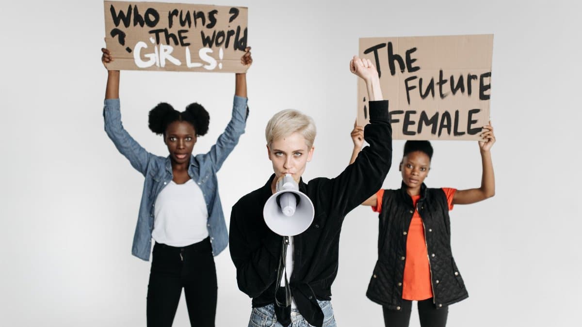 Diverse women protesting with placards and megaphone in a studio setting.