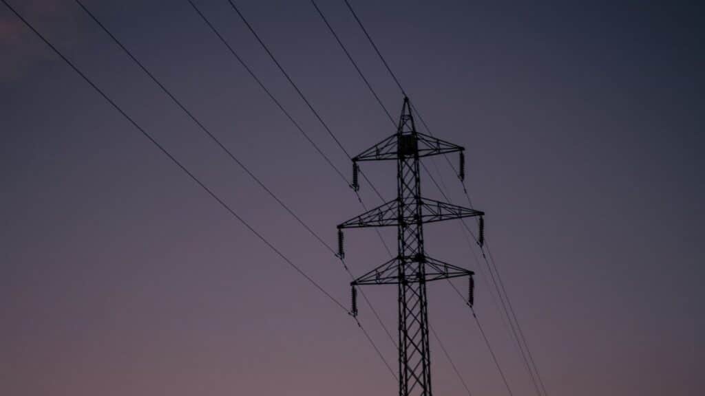 Silhouette of an electric tower against a twilight sky, representing industrial infrastructure.