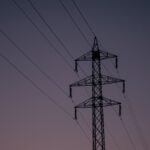 Silhouette of an electric tower against a twilight sky, representing industrial infrastructure.