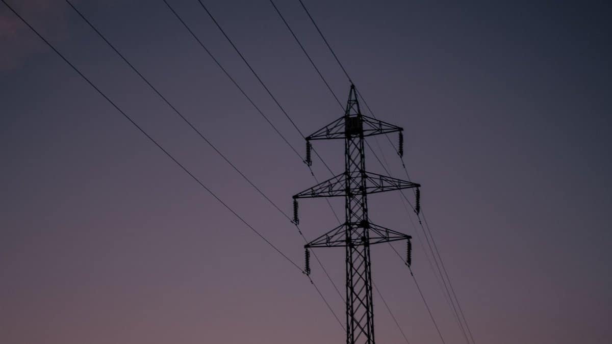 Silhouette of an electric tower against a twilight sky, representing industrial infrastructure.