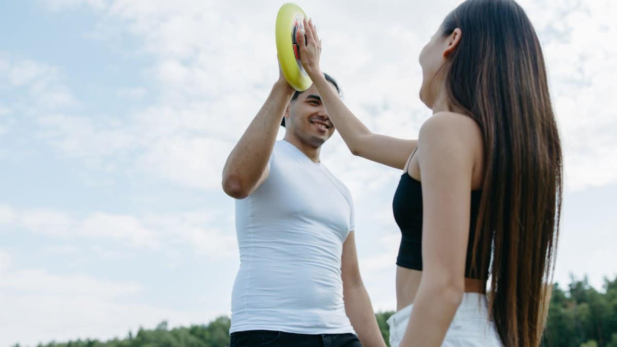 A joyful couple enjoying a frisbee game in a sunny outdoor setting.