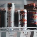 Variety of energy drinks displayed with prices on a refrigerator shelf.
