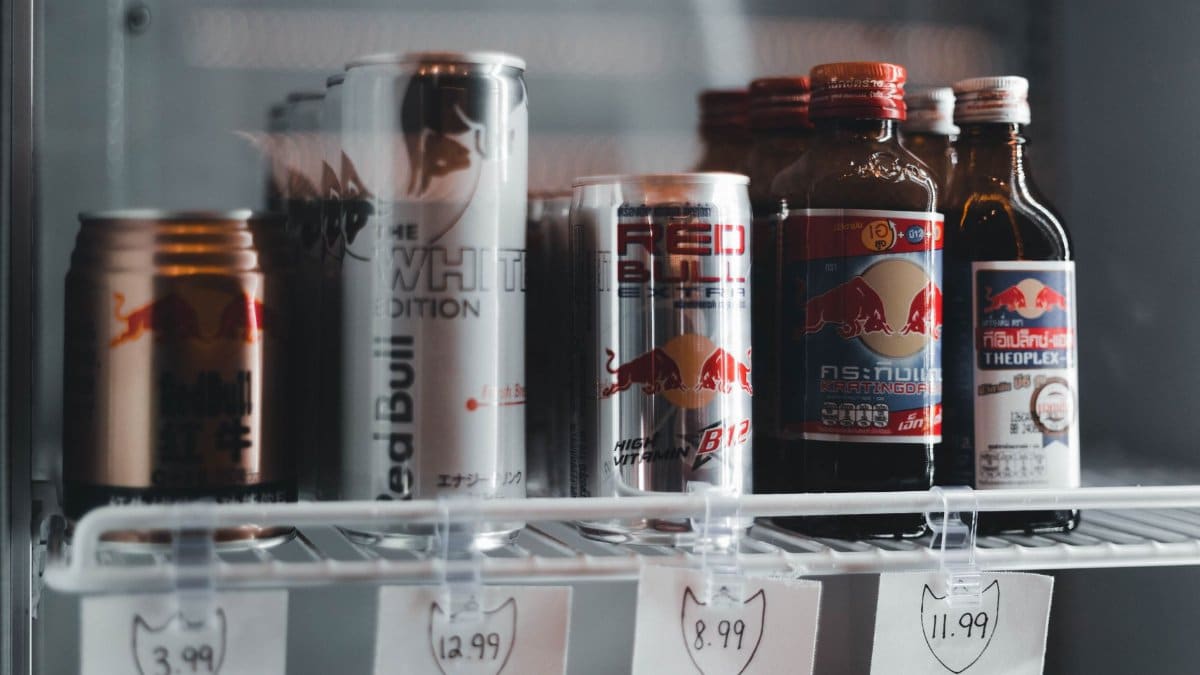 Variety of energy drinks displayed with prices on a refrigerator shelf.