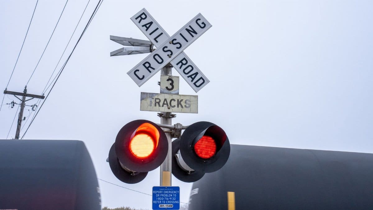 Railroad crossing with lit red warning lights and train passing in Wabasha, Minnesota.