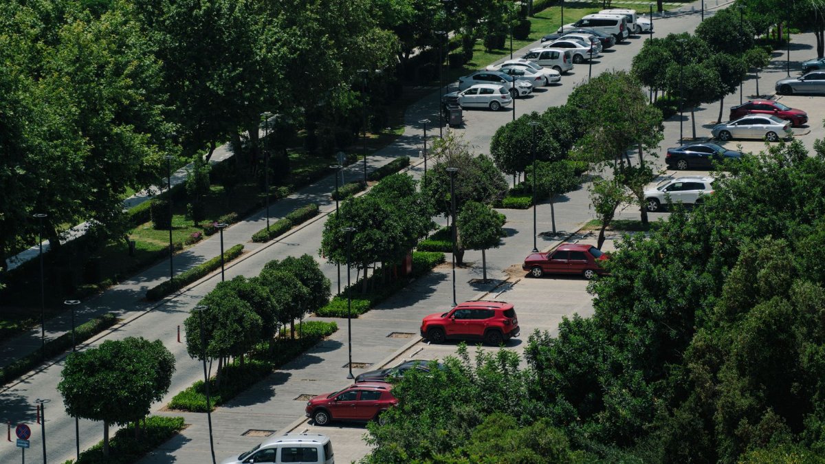Aerial view showcasing a parking lot surrounded by lush trees and parked cars.