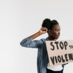 Black woman holding a 'Stop the Violence' sign in a peaceful protest setting.