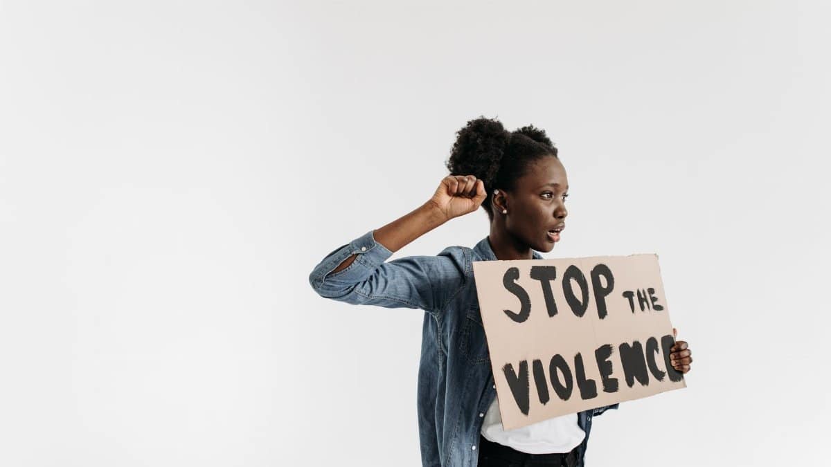 Black woman holding a 'Stop the Violence' sign in a peaceful protest setting.